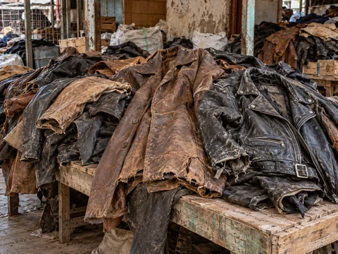 Material illustration: Worn leather jackets and coats in a second-hand market sorting area